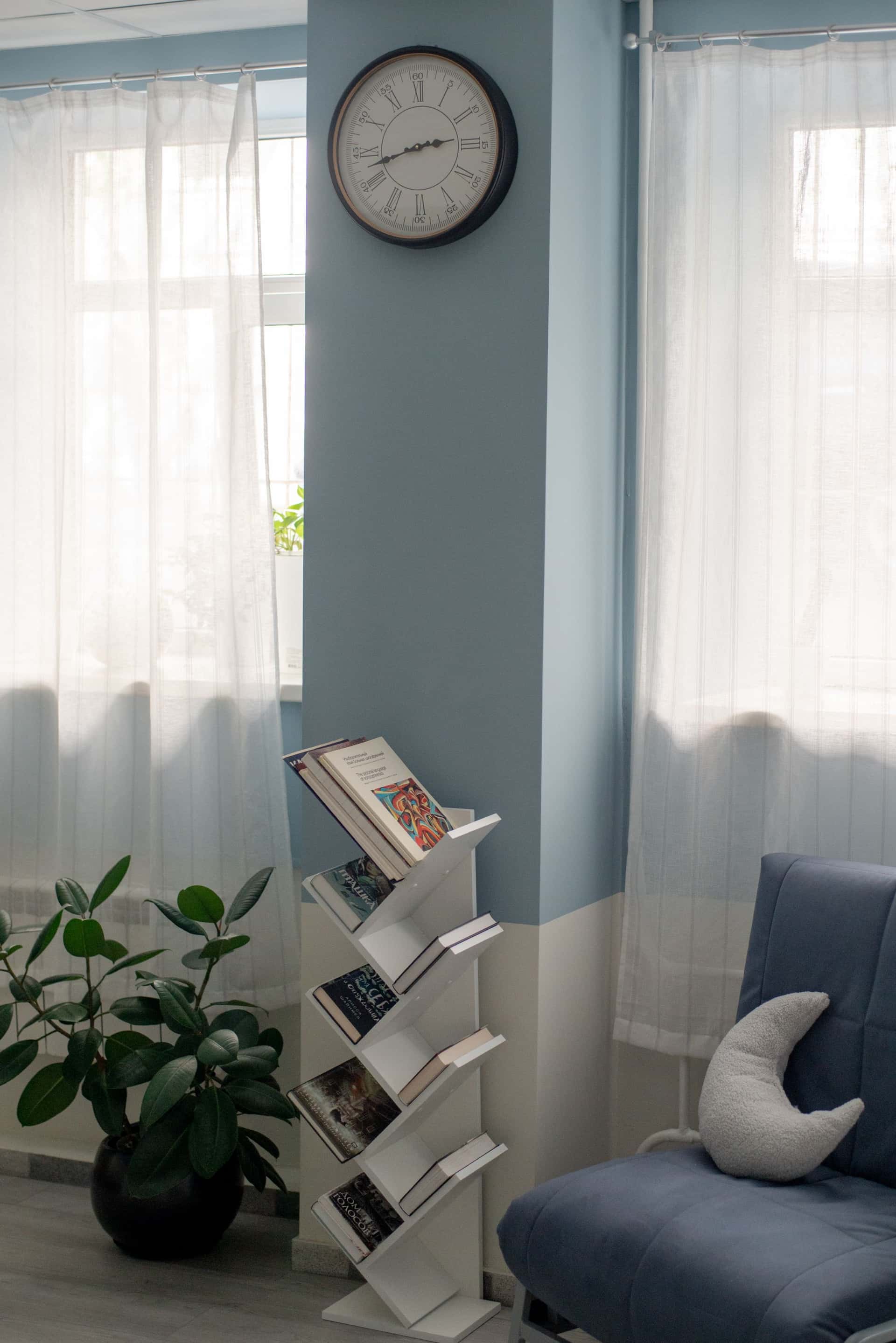 Уютная комната со стенами бледно-голубого цвета, старинными часами