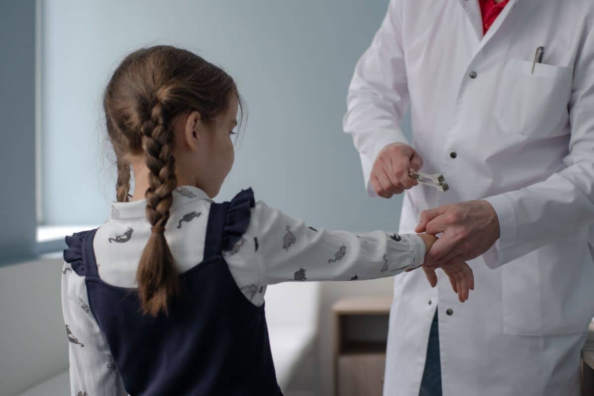 Врач в белом халате осматривает руку молодой девушки в медицинском кабинете.