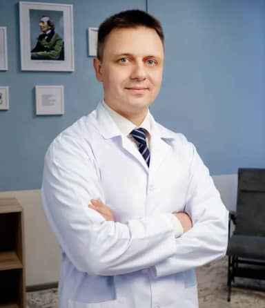 Уверенный профессионал в белом халате стоит, скрестив руки на груди