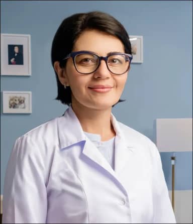 Женщина с короткими темными волосами и в очках тепло улыбается