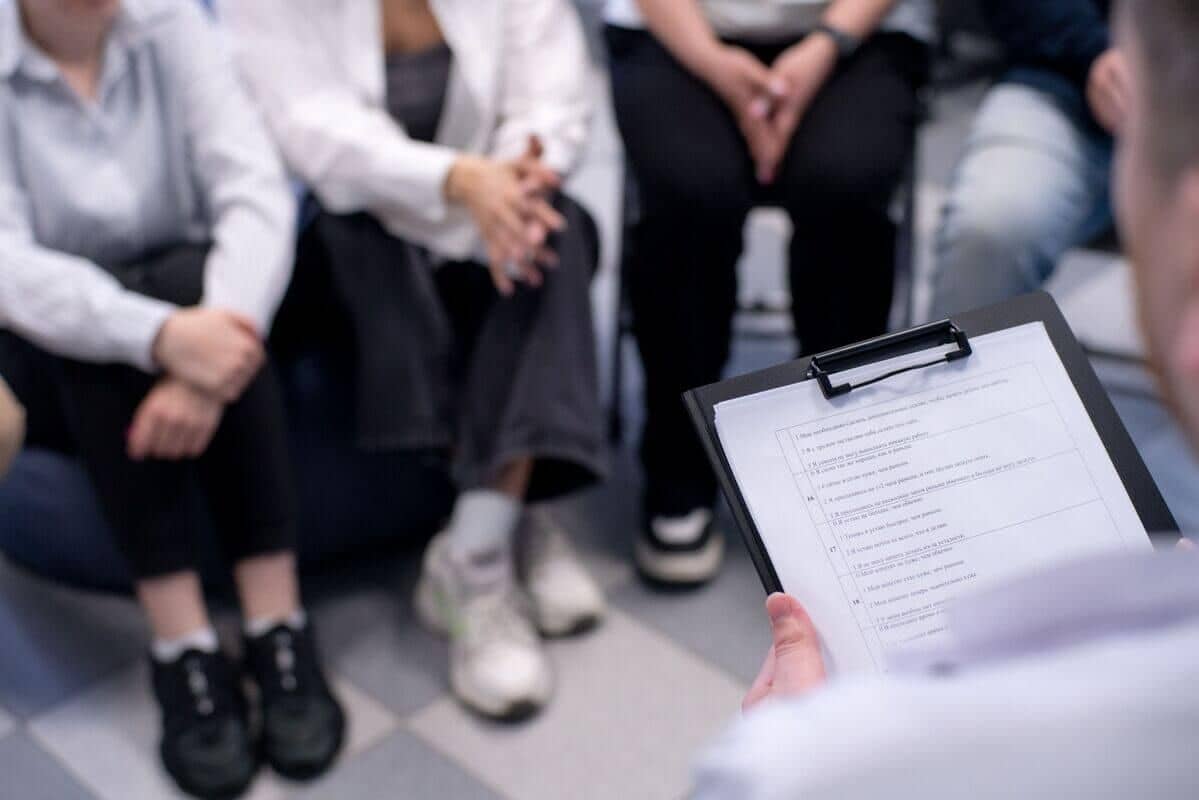 Сеанс групповой терапии: люди сидят в кругу, сосредоточившись на своих руках