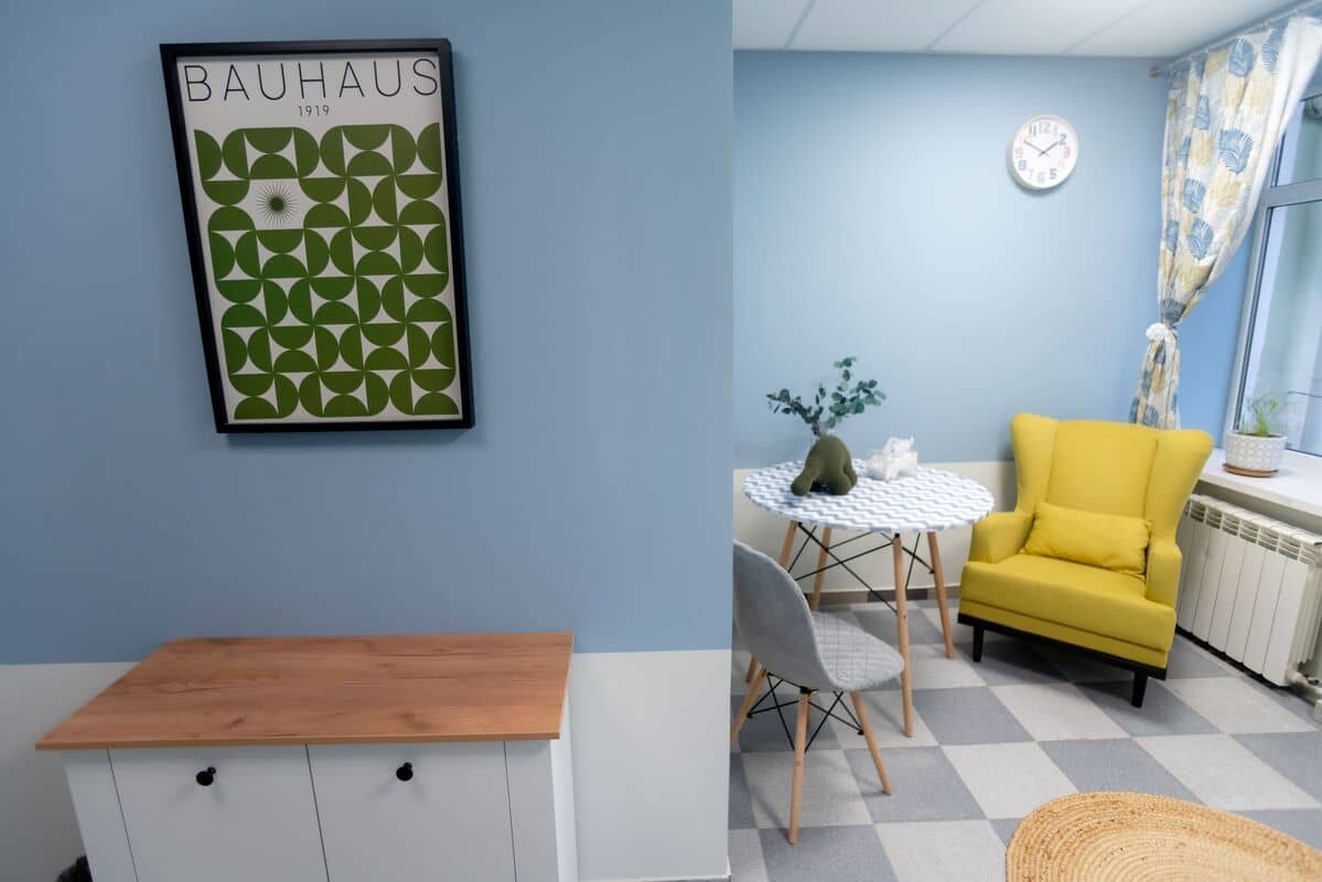 Интерьер современной комнаты со светло-голубыми стенами, желтым креслом