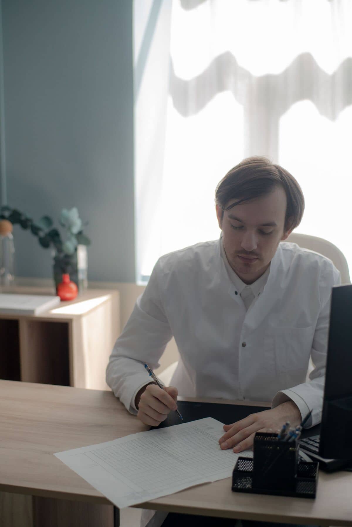 Мужчина в белой рубашке сидит за столом сосредоточенно работая над документом